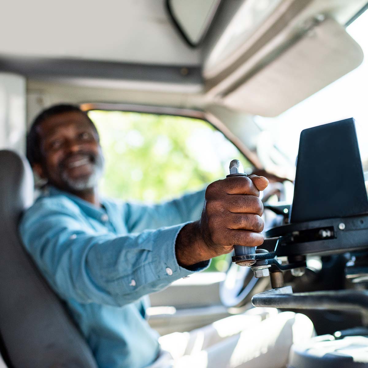 Bus driver smiles while opening the passenger door of the bus.