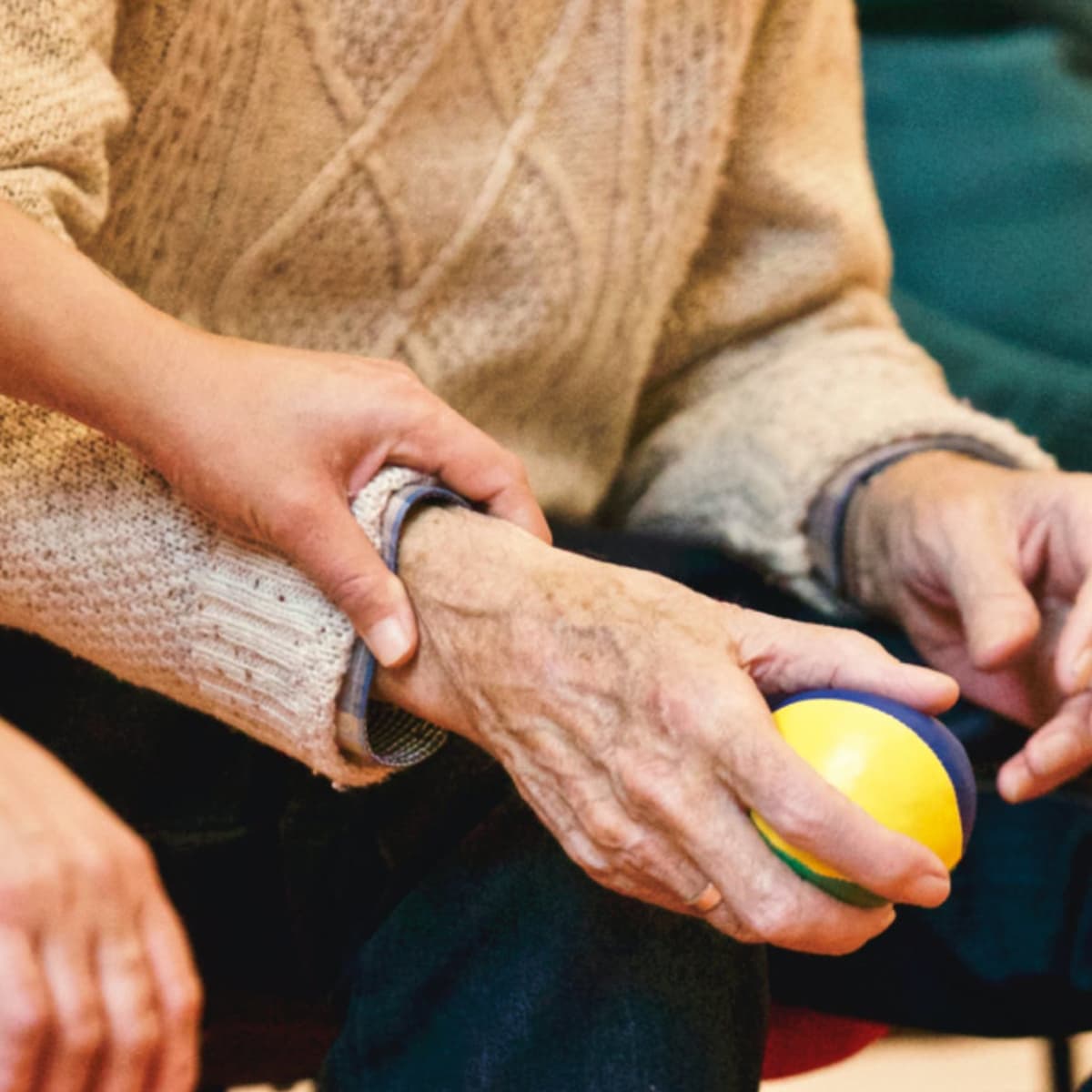 Nurse assisting a resident in hand exercises.