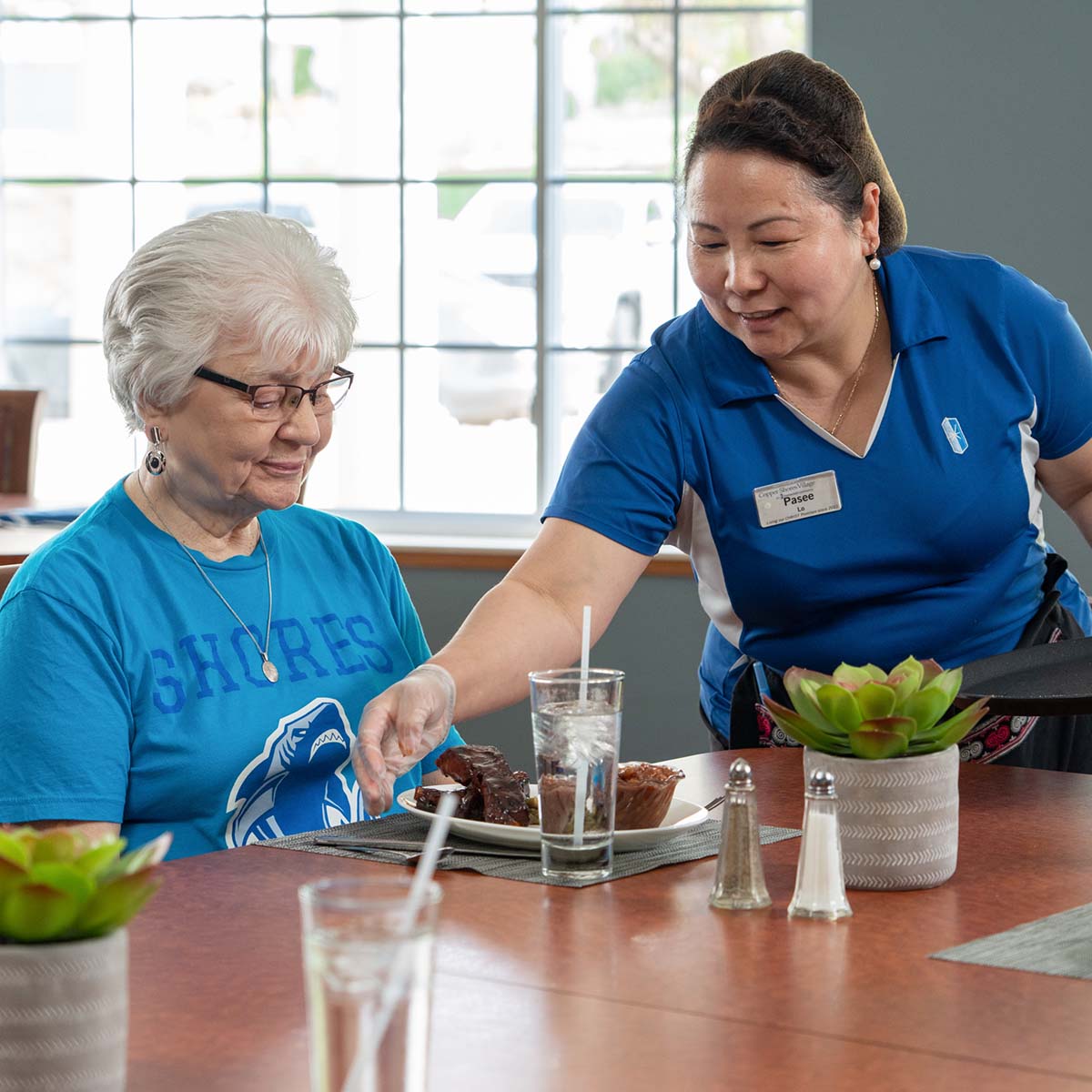 Immanuel server sets down a plate of food for a female senior.
