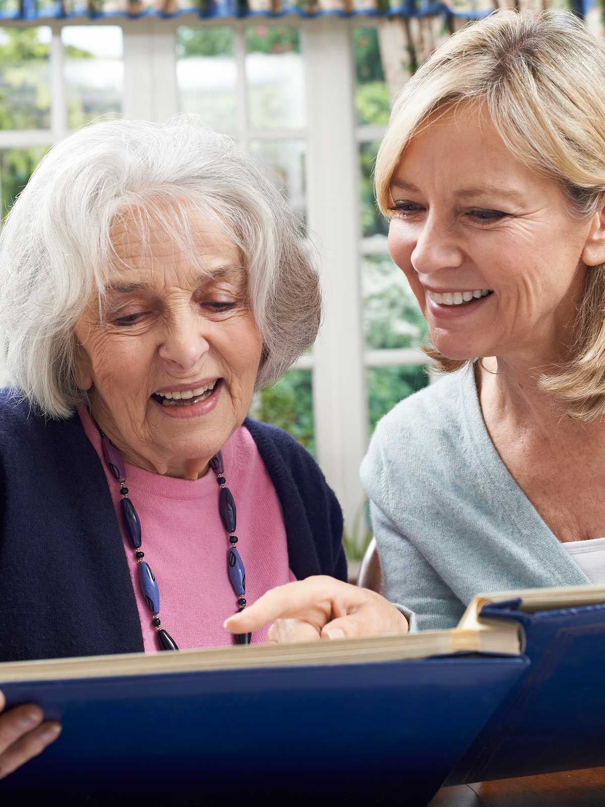 Daughter looks at photos with her senior mother.