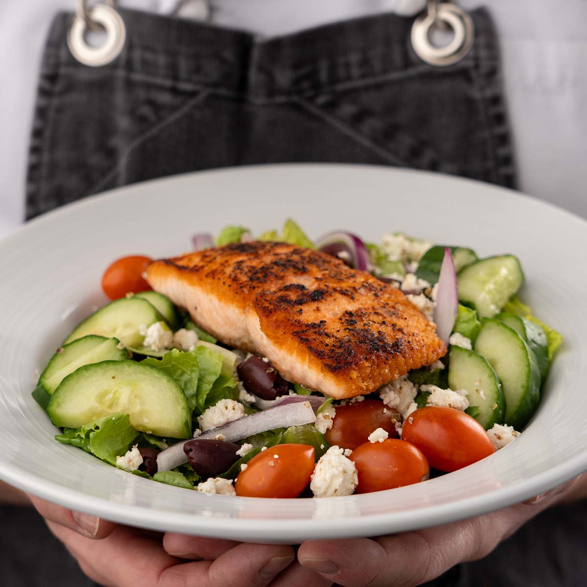 A chef holds a salmon sald dish.